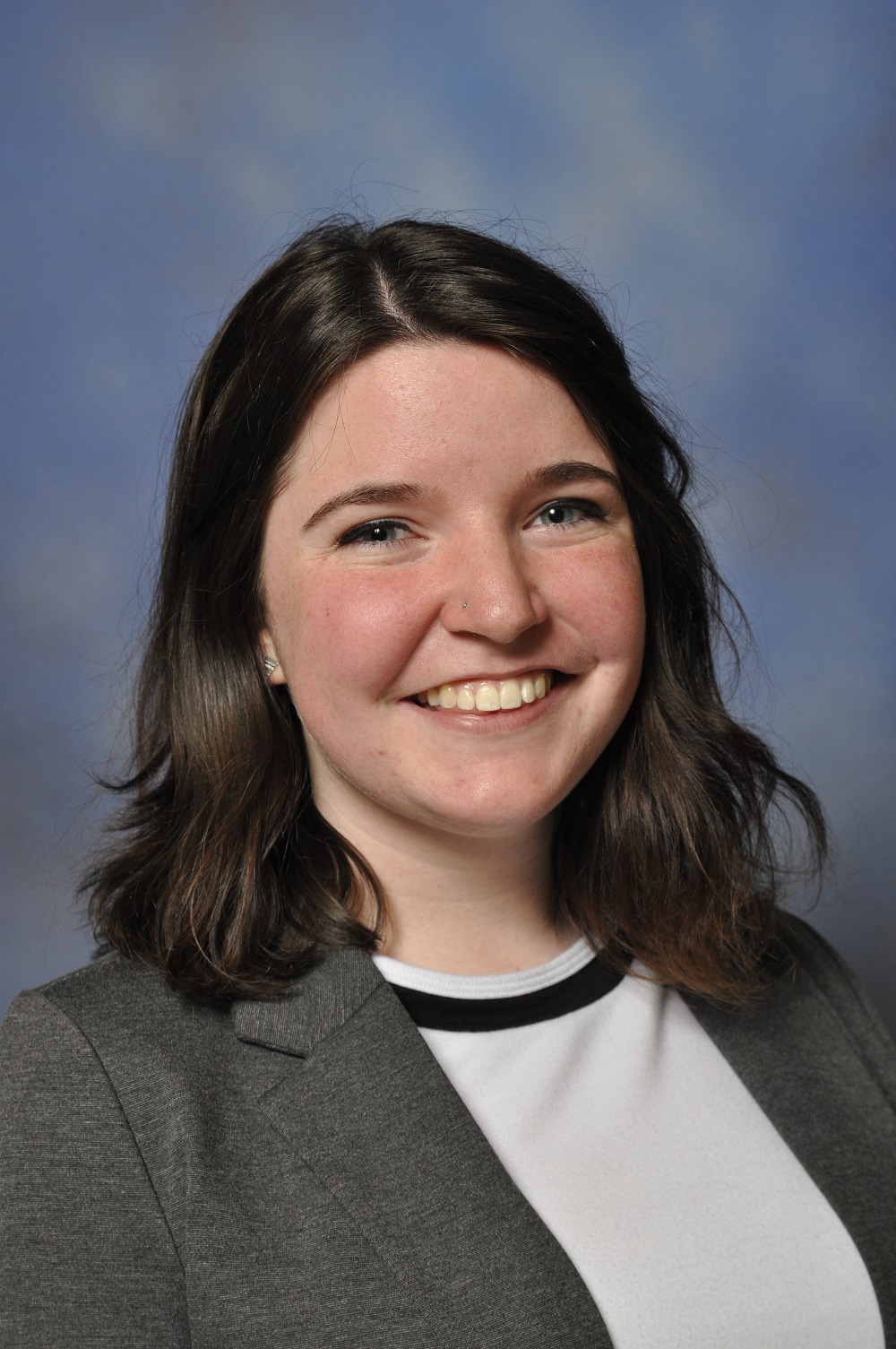 a person with brown hair wearing a grey suit jacket