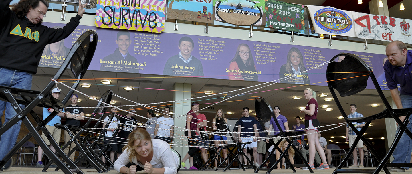 A girl performing army crawl in CSU in a set made up of chairs and ropes