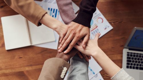 Four people stacking up their hands on top of each other