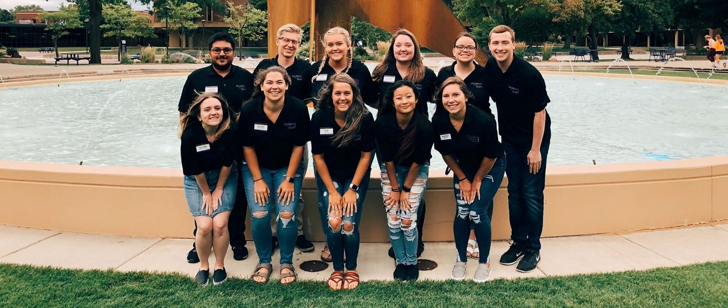 group of students posing for picture in front of the campus fountain