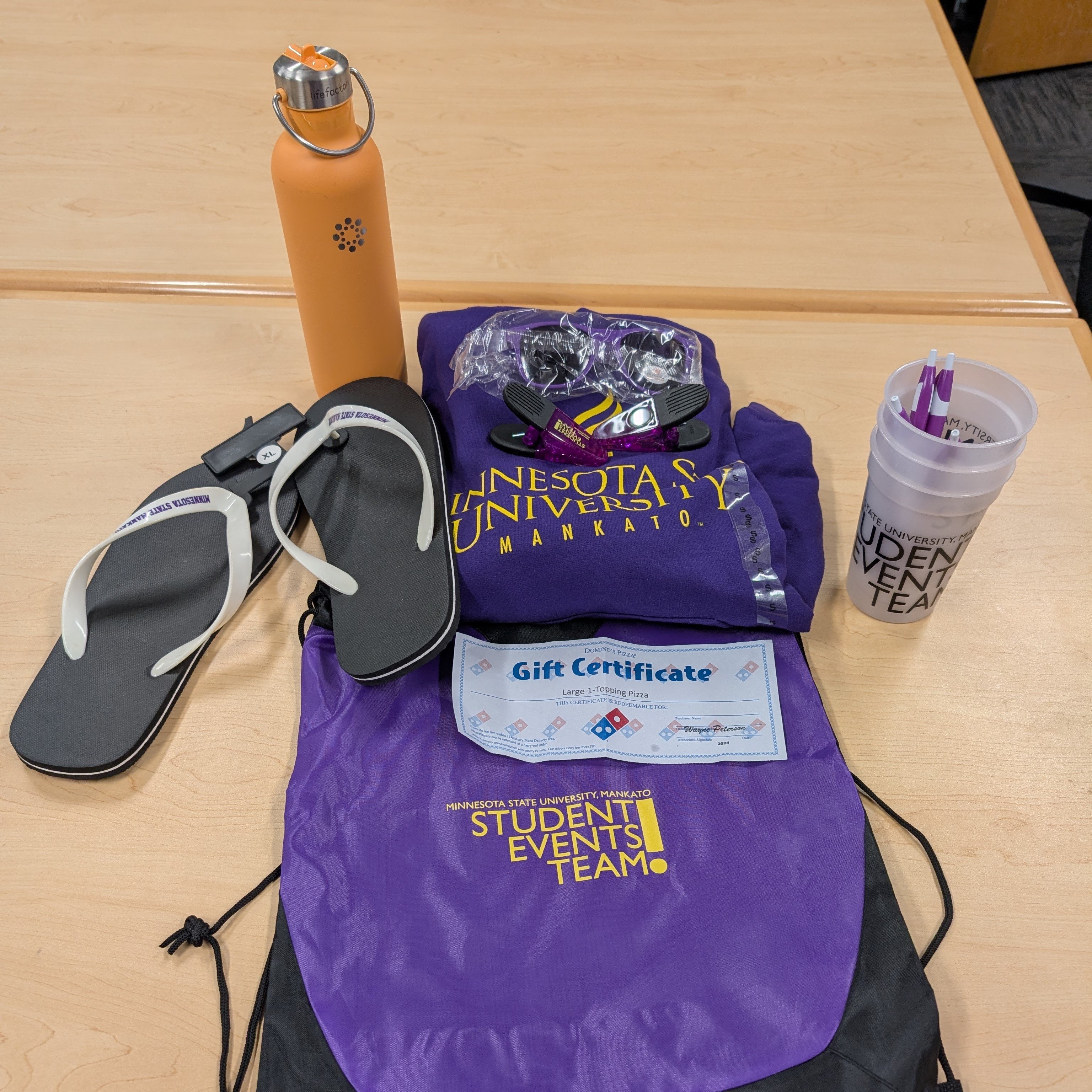 a purple bag with flip flops and a bottle of water on a table