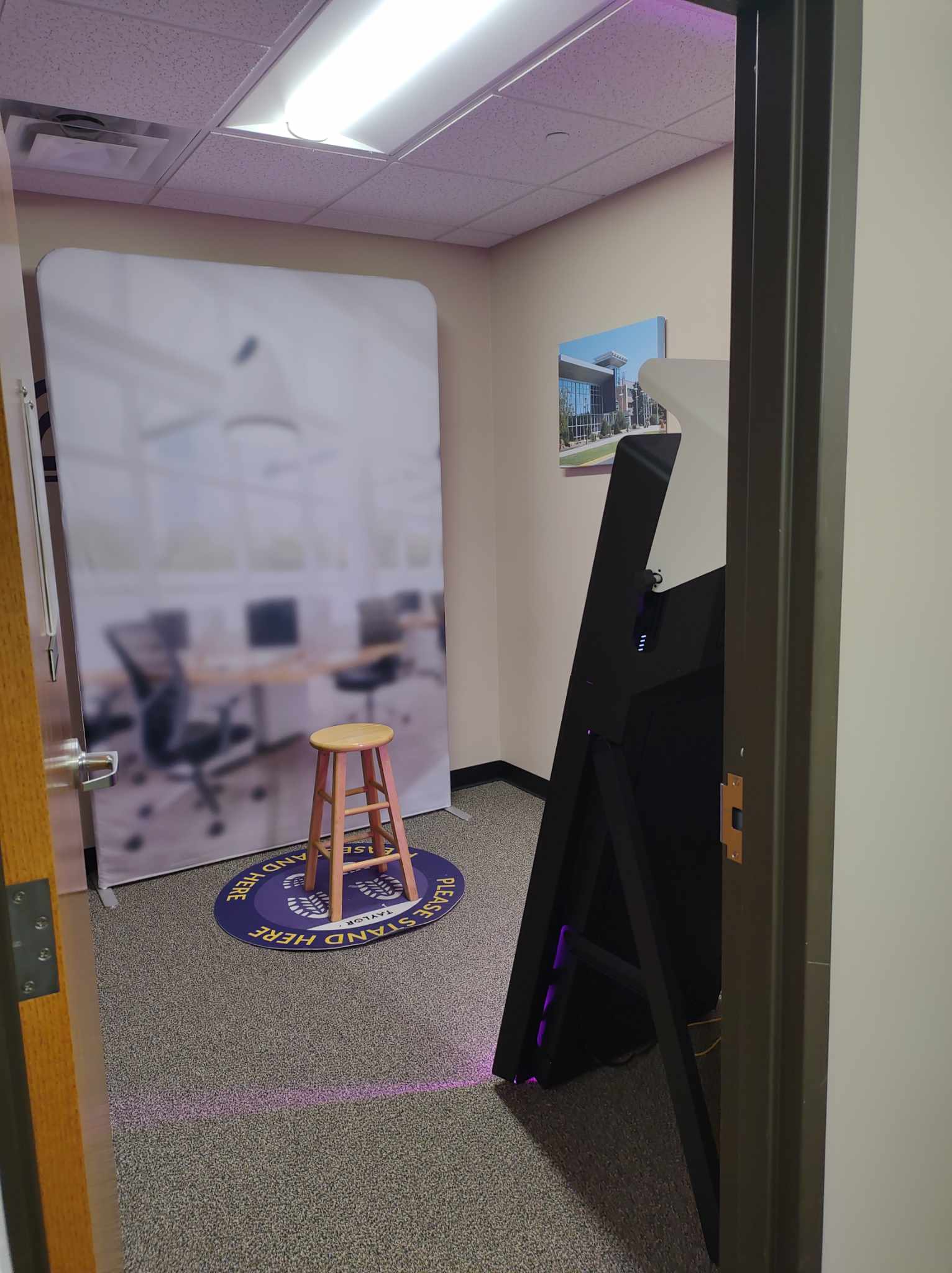 a room with a stool and a large screen