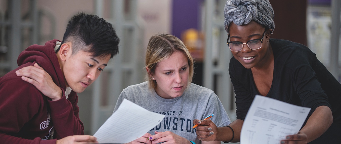 Three students working together on an assignment at a table in Memorial Library