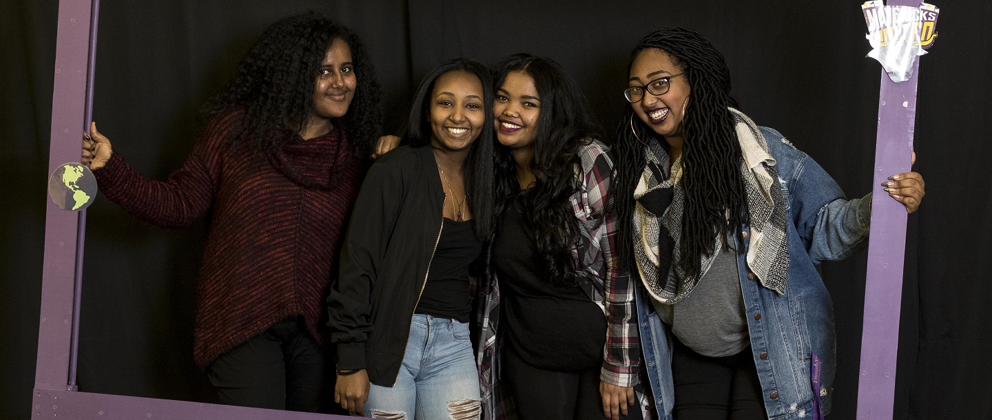 Picture of 4 students (women) posing behind a Maverick purple Frame