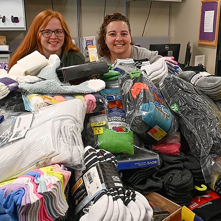 two women sitting in a room with a pile of socks and socks