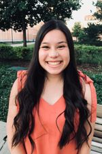 Kellie Wong posing for a photo outside on campus with trees and bushes in the background