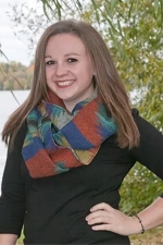 Olivia Marth posing outside for a photo with a lake and trees in the background