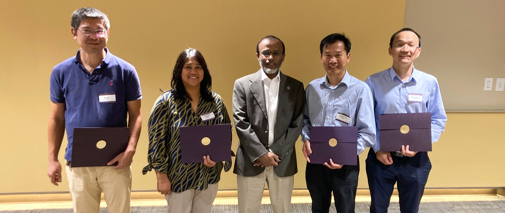 a group of people standing together and holding purple folders while looking at the camera.