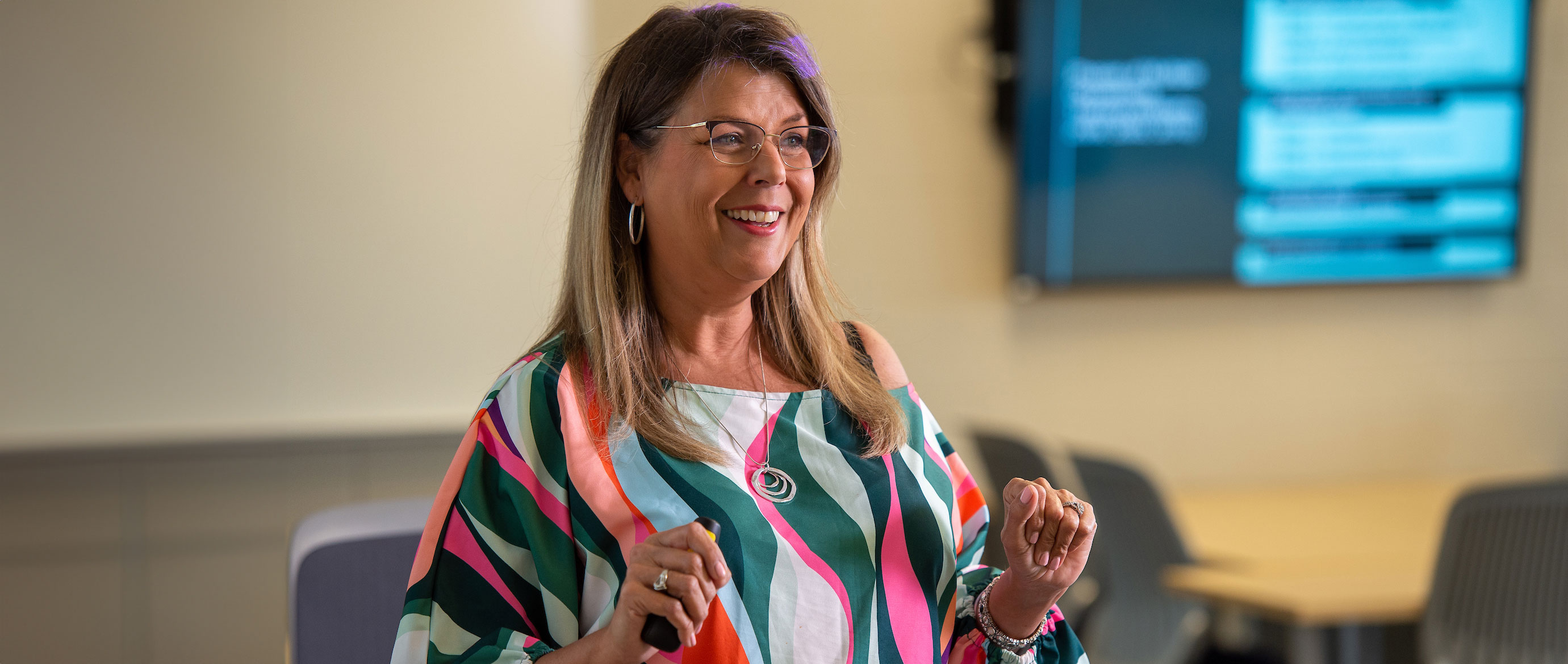 an instructor wearing glasses and in a colorful shirt smiling at students