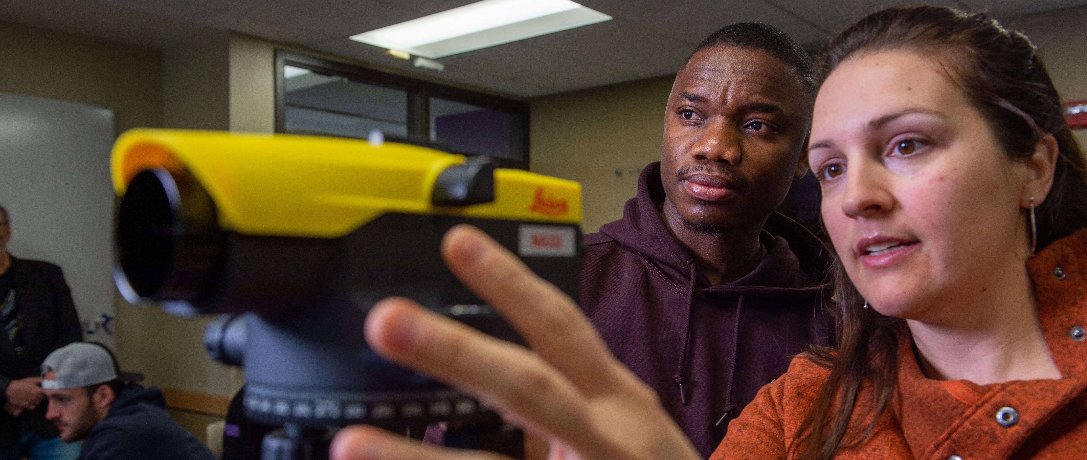 Two students looking at a piece of small equipment. 