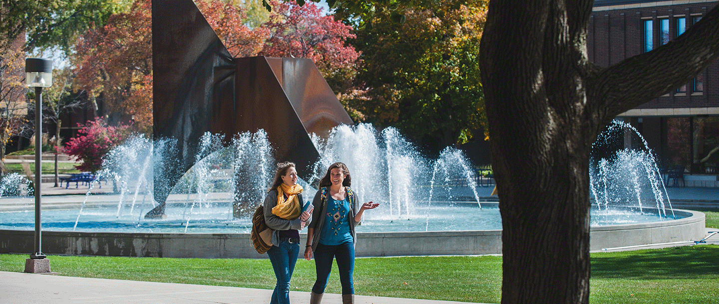 two women walking in front of a fountain