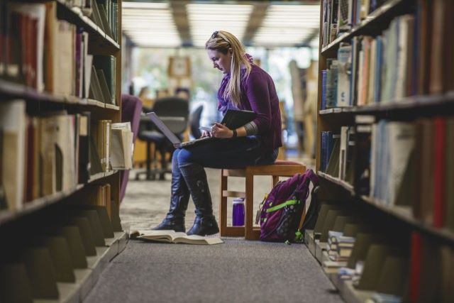 A student doing research in Memorial Library with a laptop