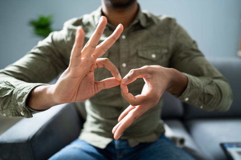 A person holding two hands close to the camera doing the American Sign Language sign for interpret.