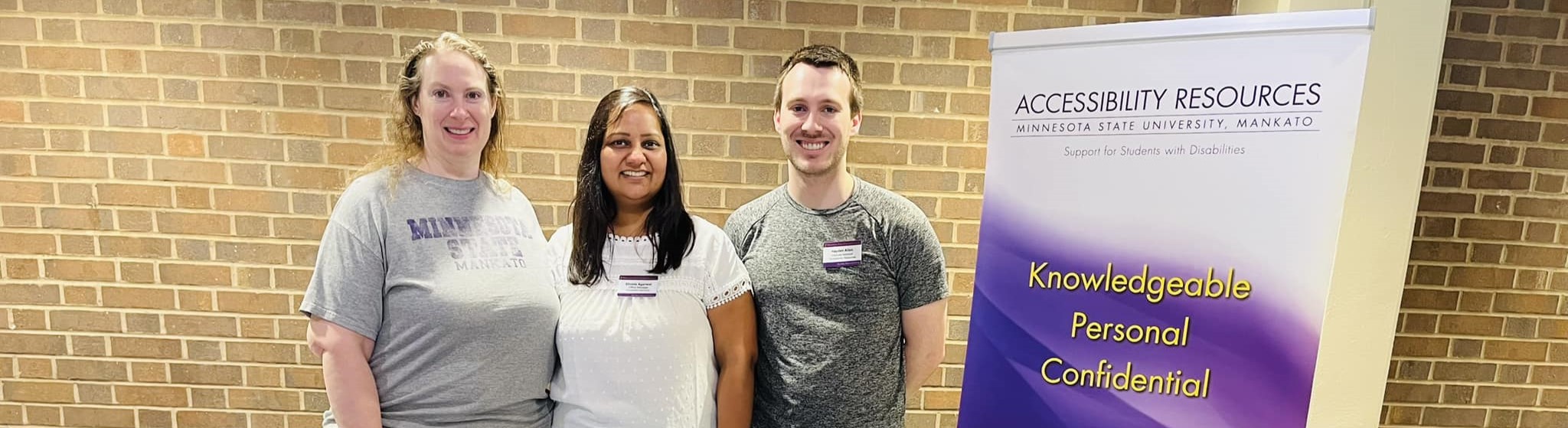 Three people standing next to an Accessibility Resources banner