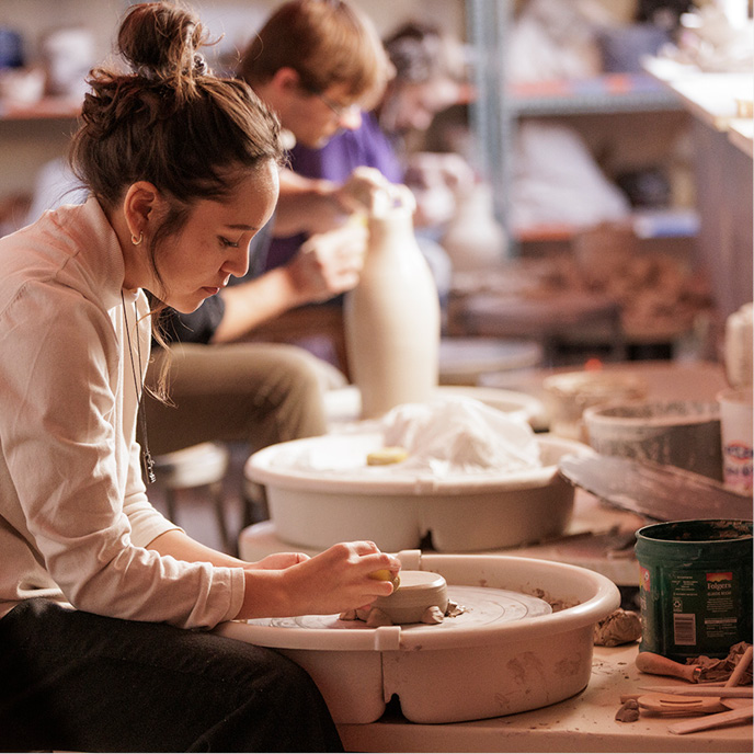 Students in a ceramic student. close up of a female student working with the clay on the wheet