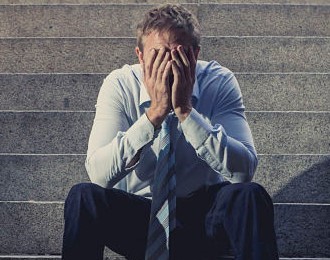 a man sitting on some steps with his hands over his face