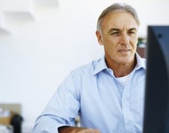 A man sitting at the desk in an office looking at the computer