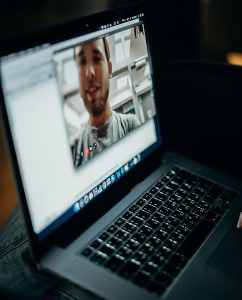 A student video chatting with his friend on a macbook