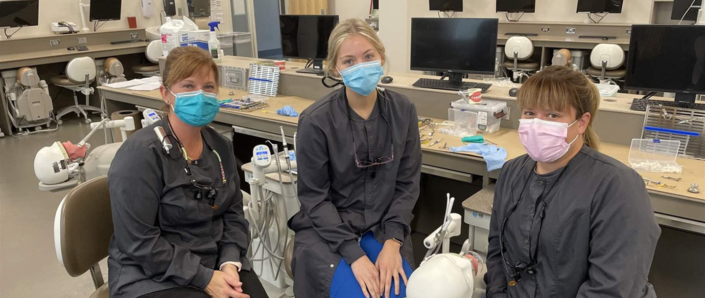 a person wearing a mask and sitting in a room with other people