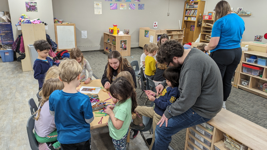 a group of children and a person and person in a classroom