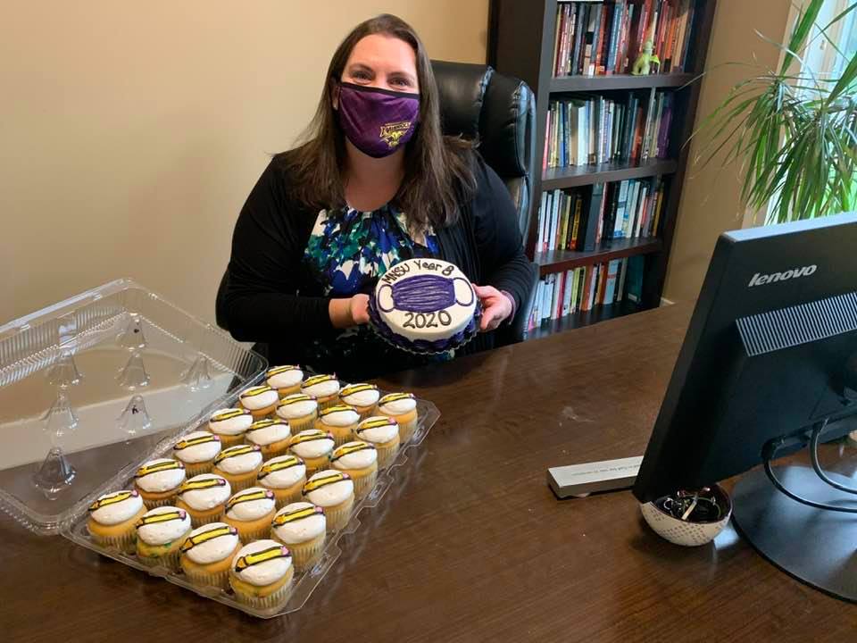 a person in a black chair with a face mask holding a plate with a cupcakes