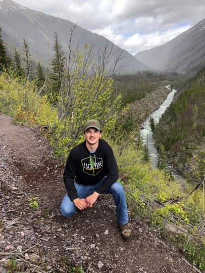 a person sitting on a dirt path with mountains in the background