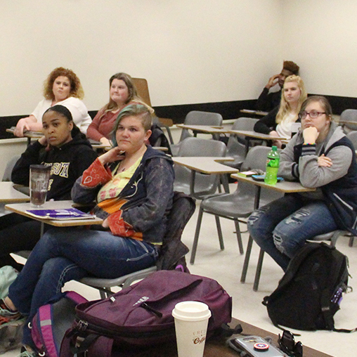 a group of people sitting at desks in a classroom