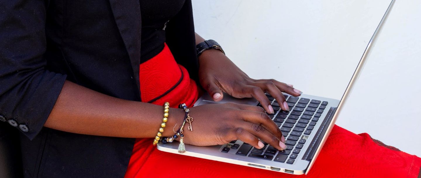 a woman sitting down and typing on her laptop