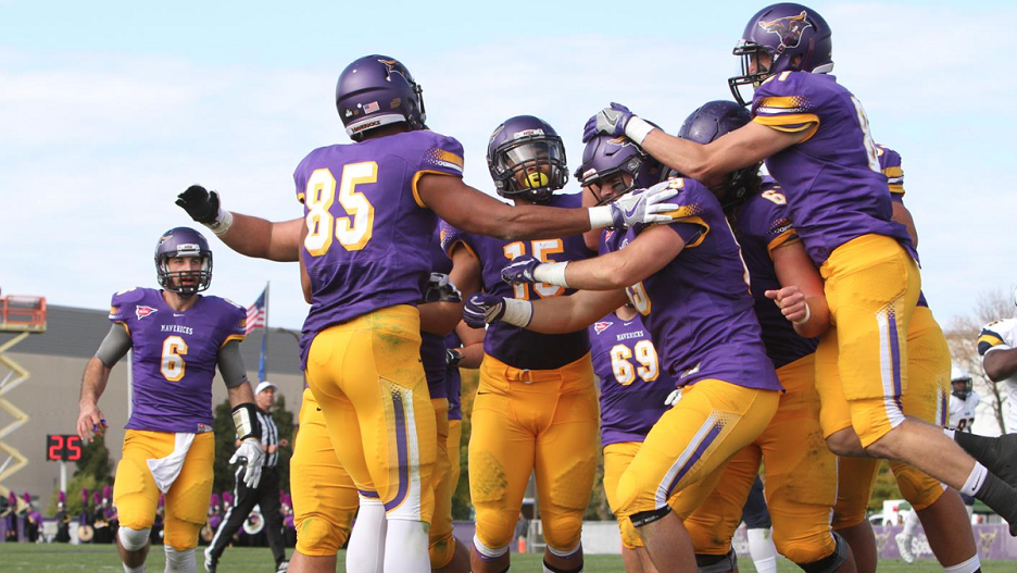 Maverick football team players grouped together in celebration after a play