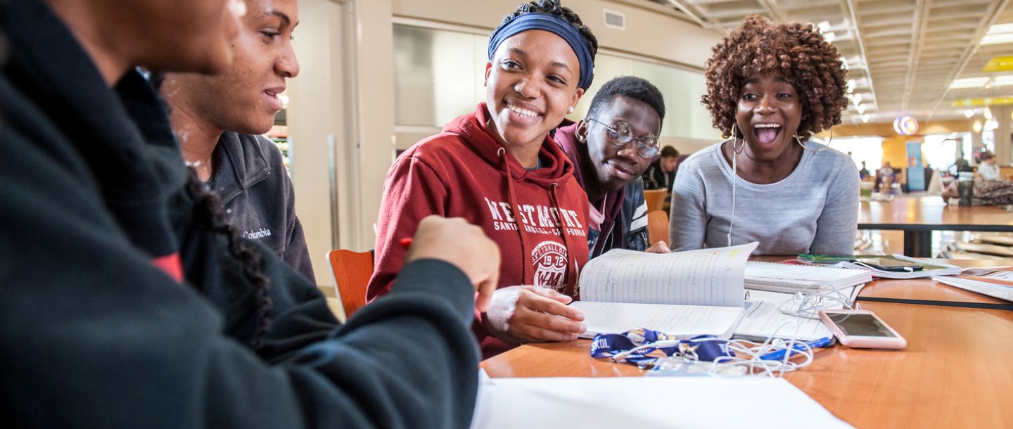 Students on campus at a table with notebooks studying together