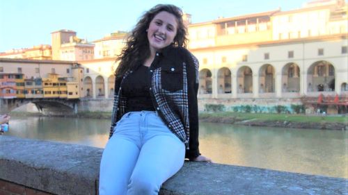 Jenna Holman sitting on the Ponte Vecchio overlooking the Arno River in Florence Italy