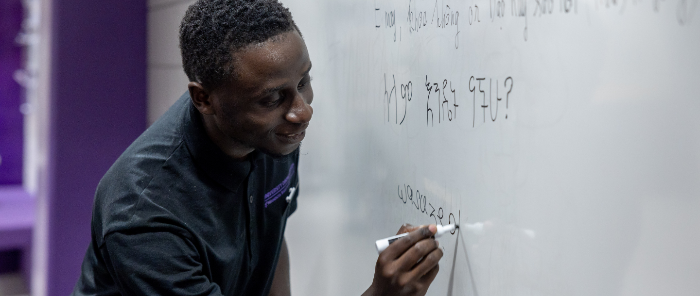 An instructor writing on a whiteboard in the classroom