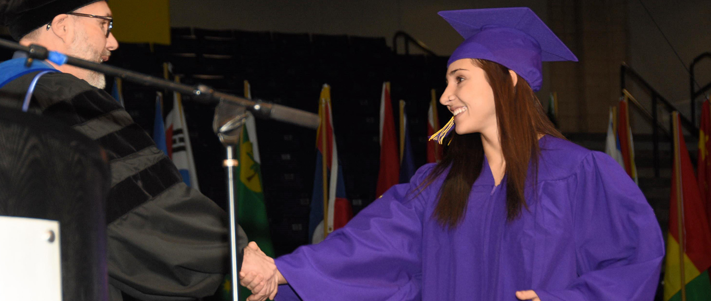 Graduate shaking hands with the provost during commencement