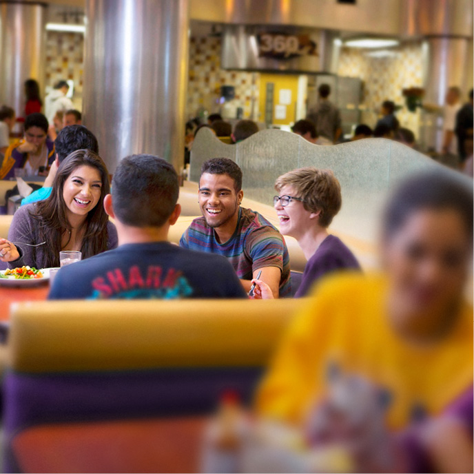 Students sitting in a booth at the Dining Center eating and Laughing