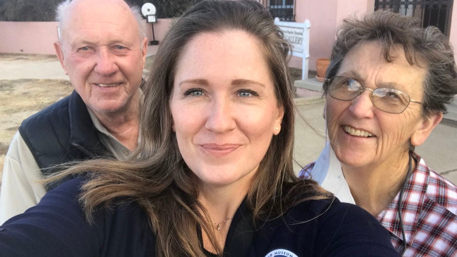 Sociology professor Kristi Rendahl posing with her parents, David and Laura Rendahl, outside on the lawn with smiles