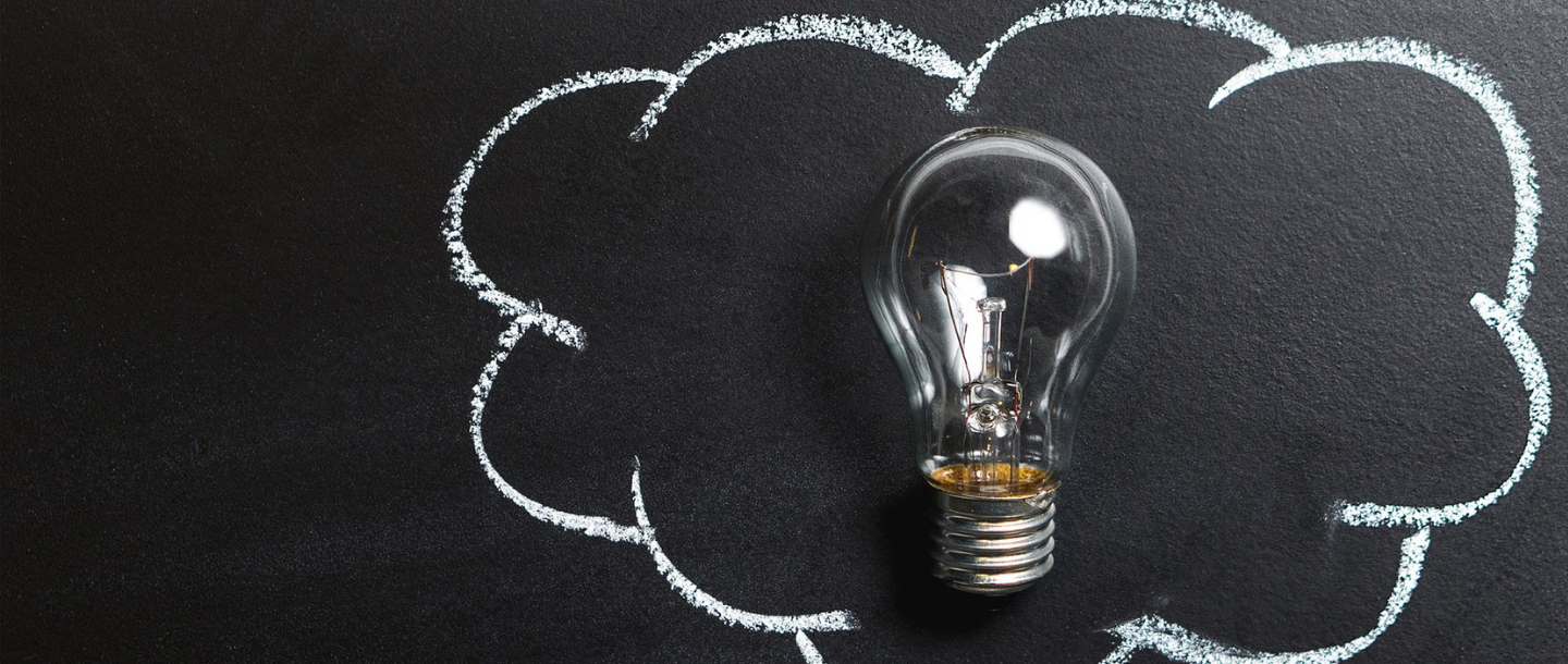 A light bulb inside a cloud shape drawn on a black board