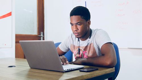 Student with laptop studying at desk