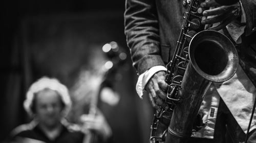 Close up of a man playing the saxophone with other jazz band members in the background