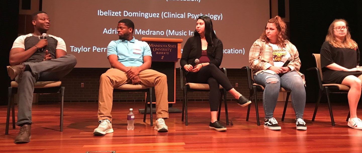 Five students, on a stage, giving a presentation