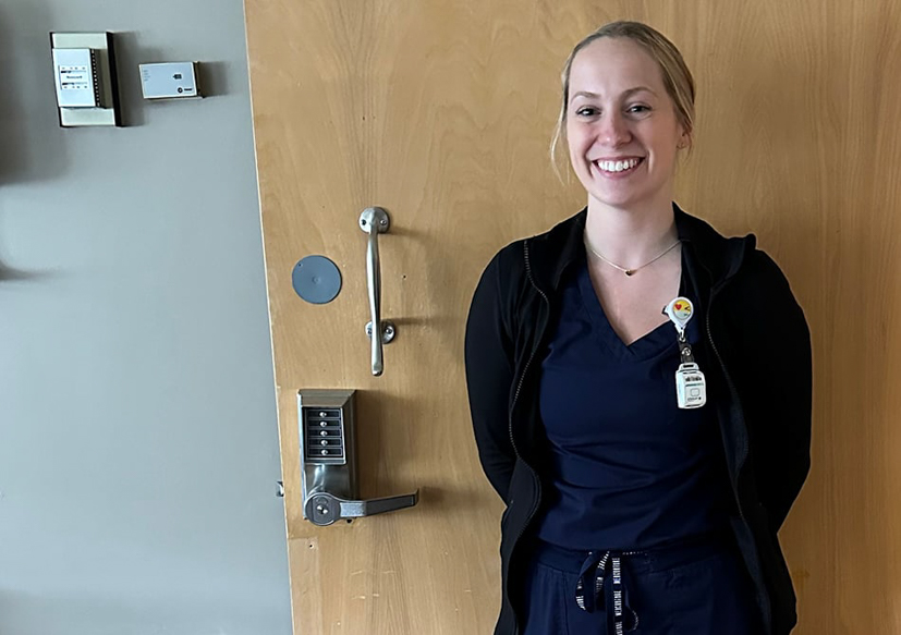 Nurse standing in front of a door in the hospital.
