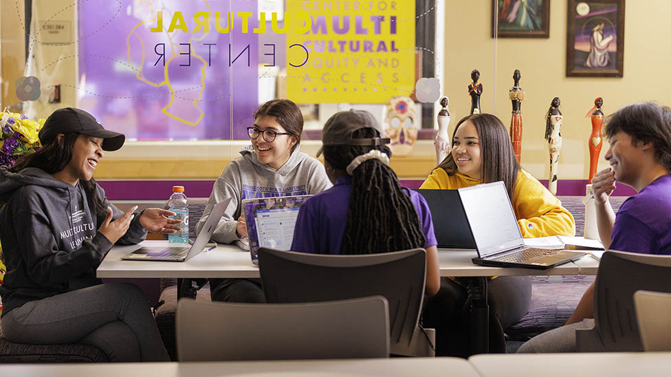 Five students sitting around a table in the MultiCultural Center