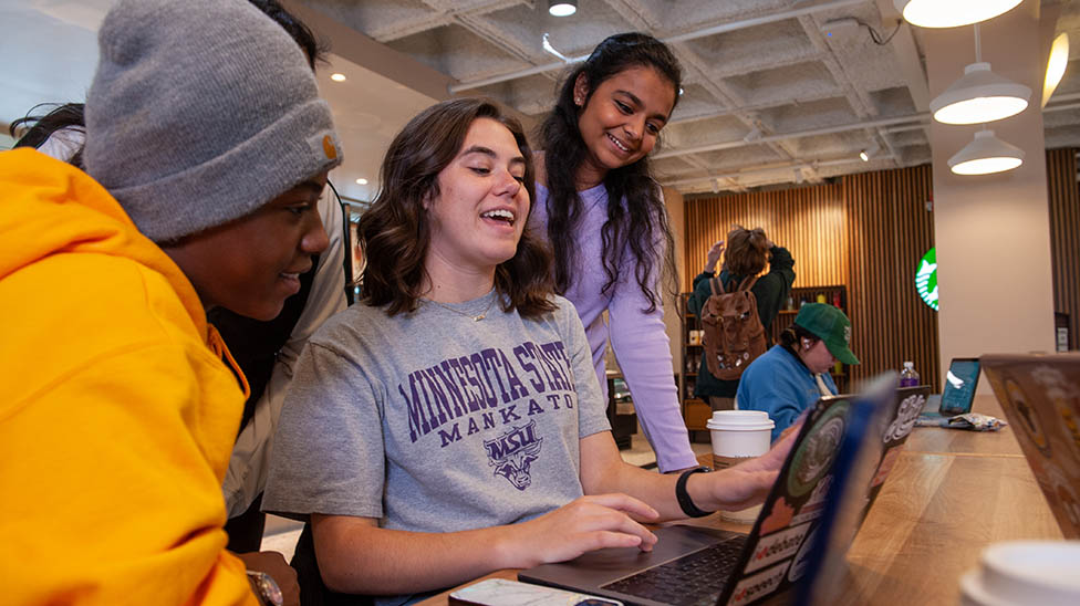 students gathered together sitting at a table laughing