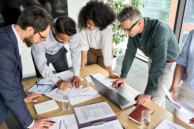 Group standing over a table talking about plans. 