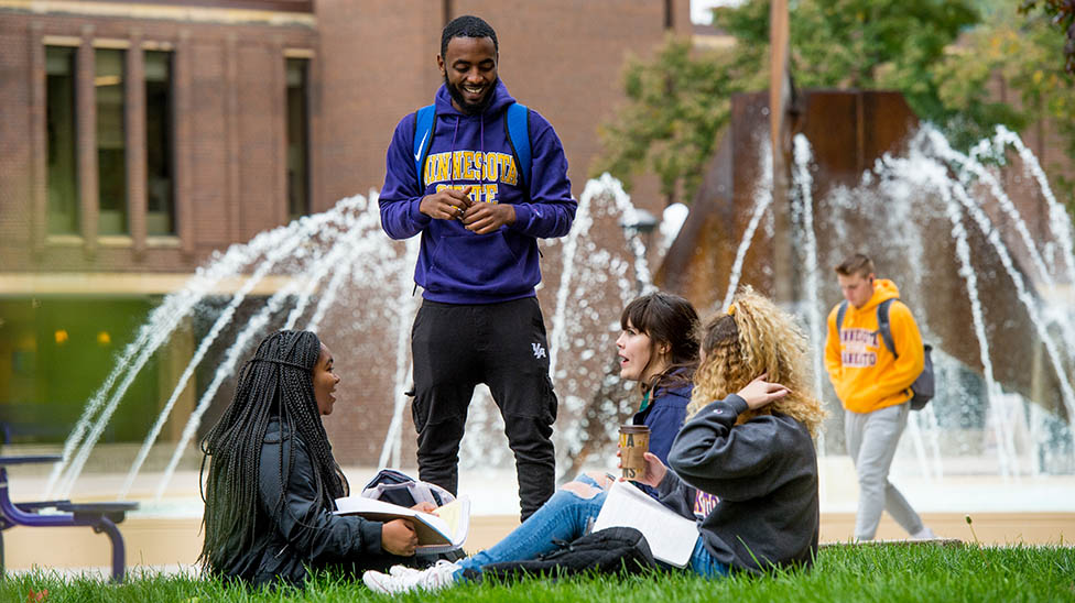 four students hanging out around the fountain near the CSU. Talking and studying together