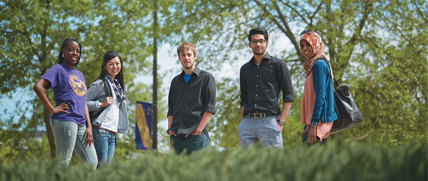 5 diverse students posing outside on campus