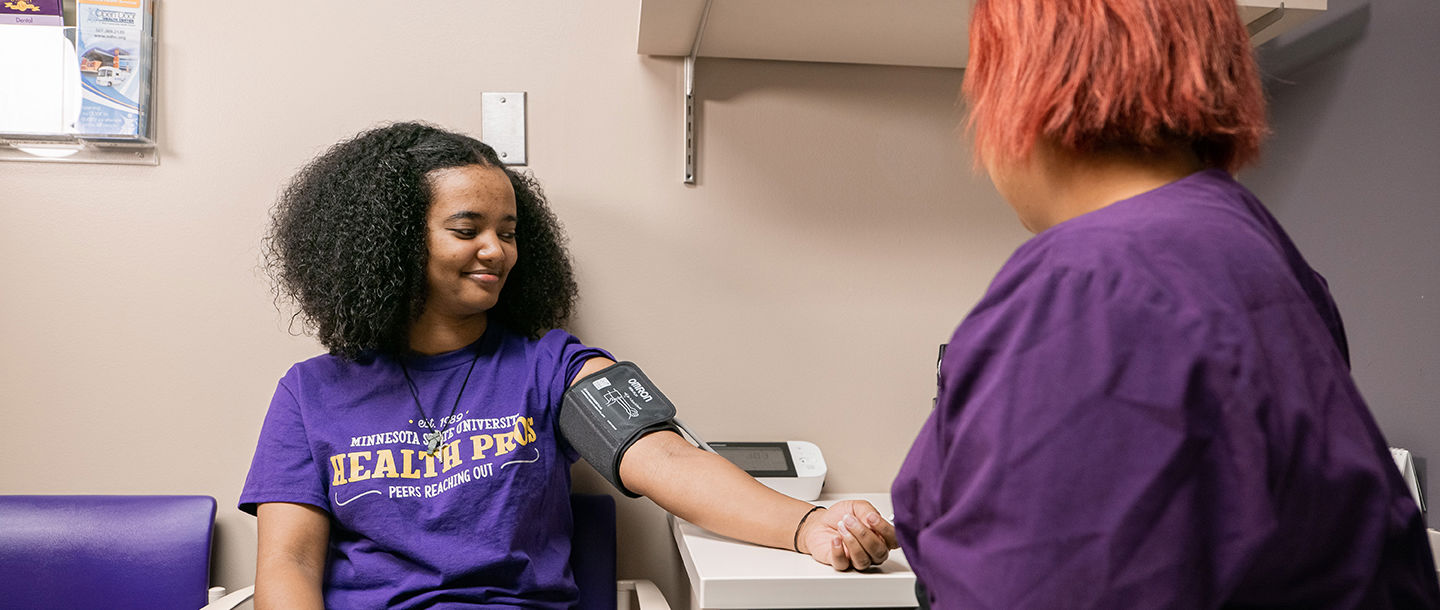 A Student Health Services nurse checking the blood pressure on a female student patient