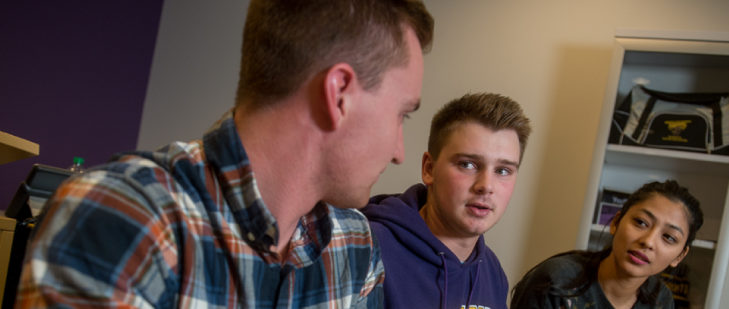 Three students sitting in a meeting room having a conversation