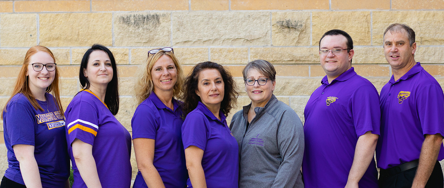 A group of people smiling in front of a brick wall