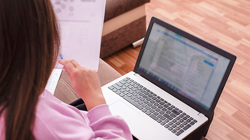 A student preparing for University studies by studying the article on printouts and with laptop