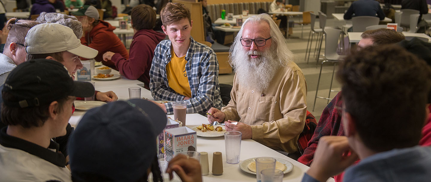 Students talking to a faculty member at a table in the dining center